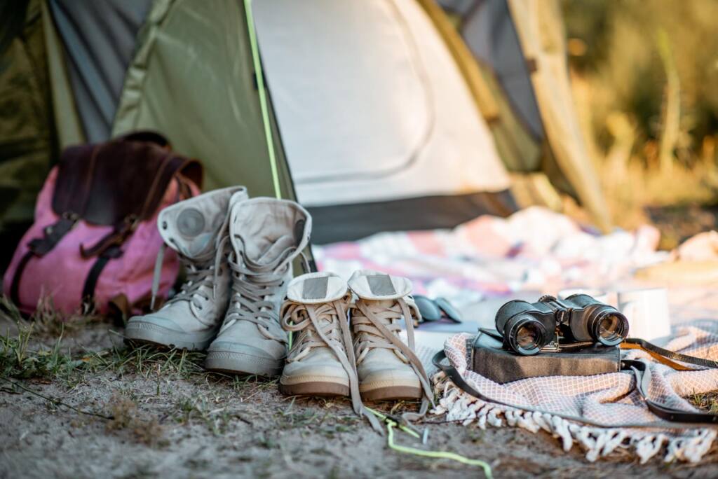 Buty trekingowe oraz lornetka jako podstawowe rzeczy pod namiot.